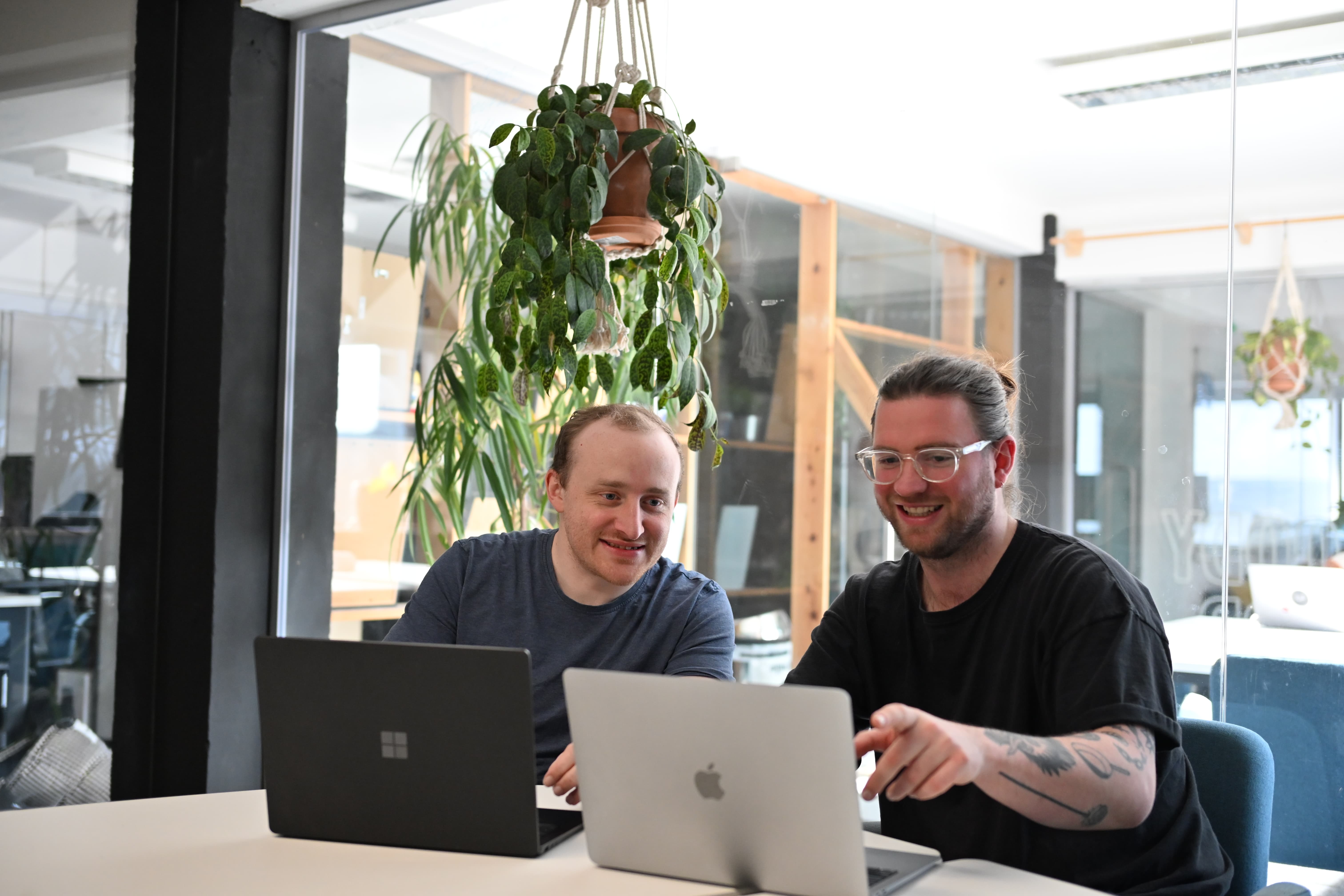 Jack and Max from Tandem sit in an office smiling at a laptop